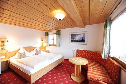 Zimmer mit drei Betten unter Holzbalkendecke